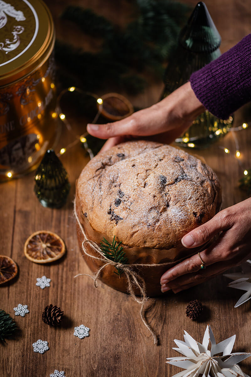 Panettone servie sur une table en bois dans une ambiance hivernale et chaleureuse.