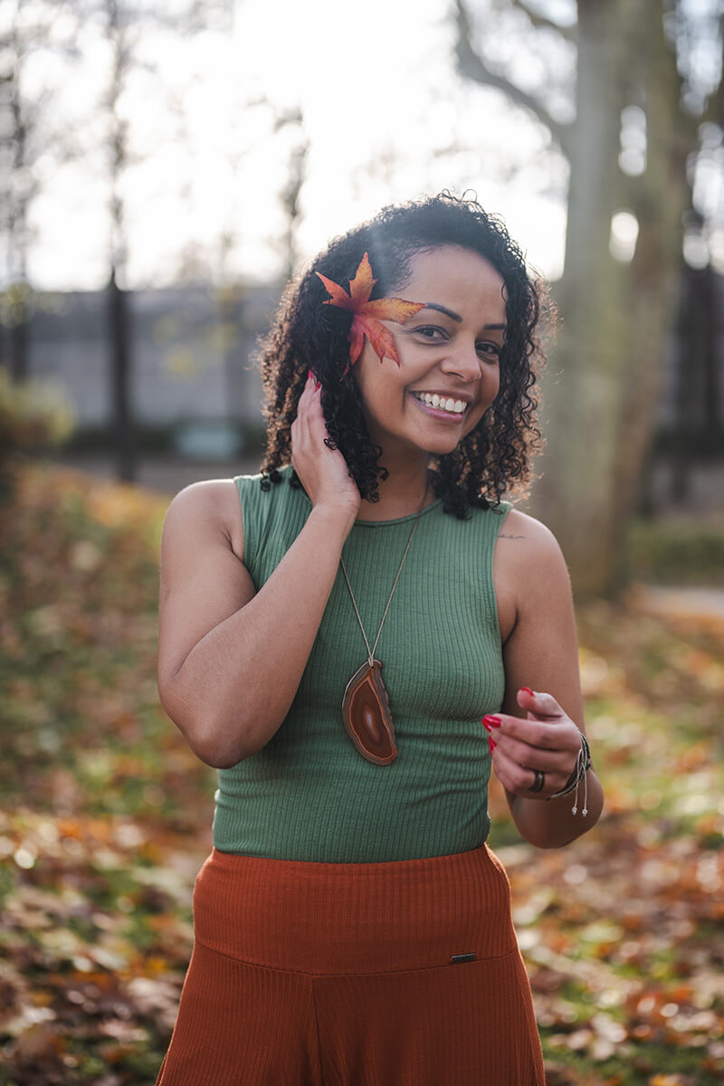 Portrait souriant de Jennifer, coach de yoga, à l'extérieur dans un décor automnal et ensoleillé.