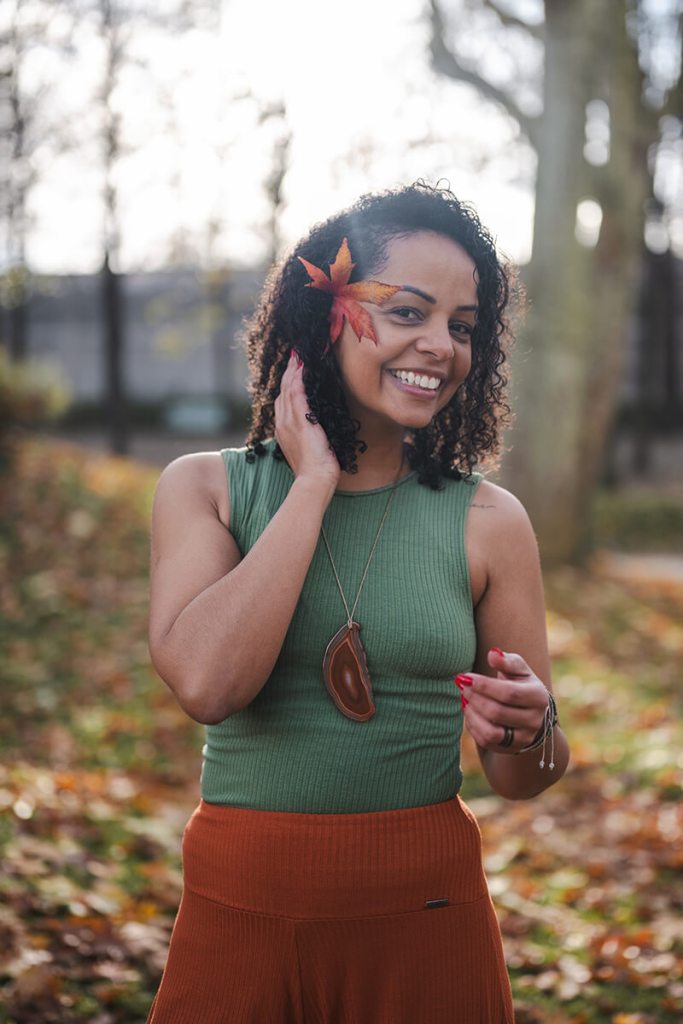 Portrait souriant de Jennifer, coach de yoga, à l'extérieur dans un décor automnal et ensoleillé.