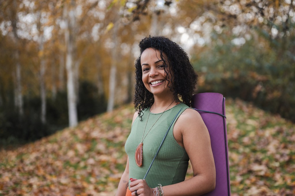 Portrait souriant de Jennifer, coach de yoga, à l'extérieur dans un décor automnal.