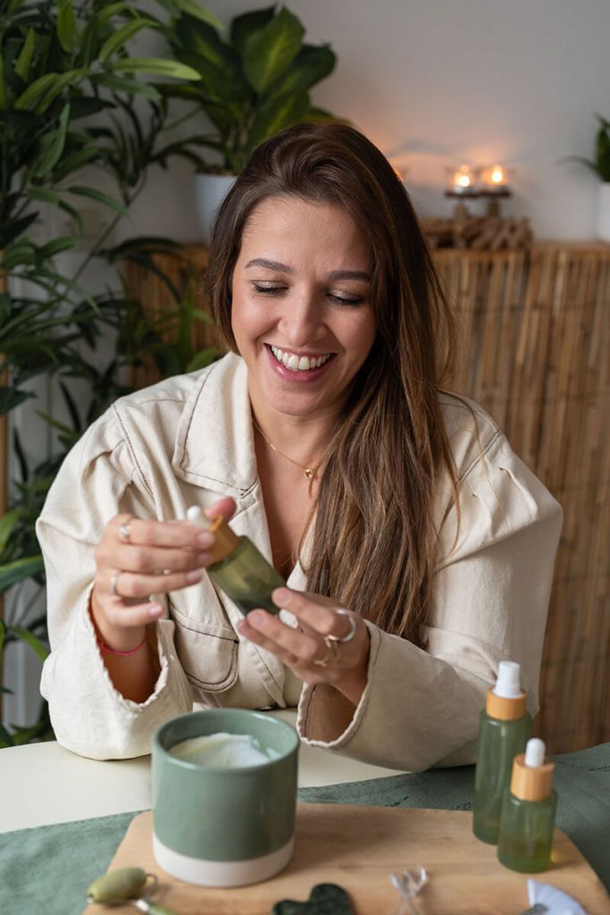Une jeune femme souriante tenant un flacon de produit pour le visage dans une ambiance relaxante.