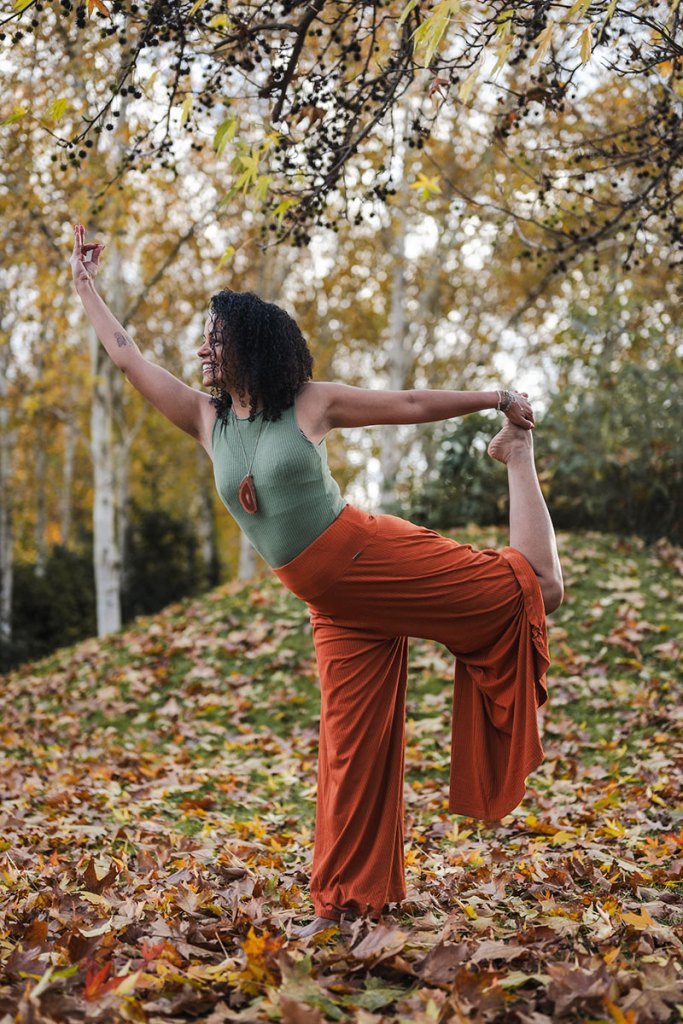 Portrait de Jennifer, coach de yoga, en équilibre sur une jambe dans un décor automnal.
