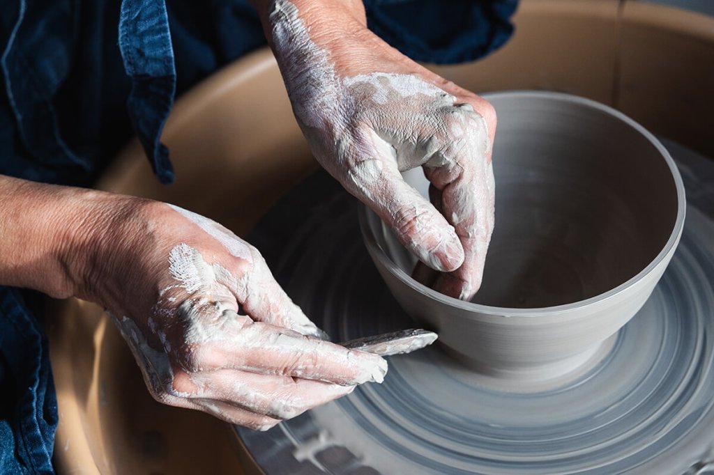 Mains d'une céramiste modelant un bol en argile sur un tour de potier.
