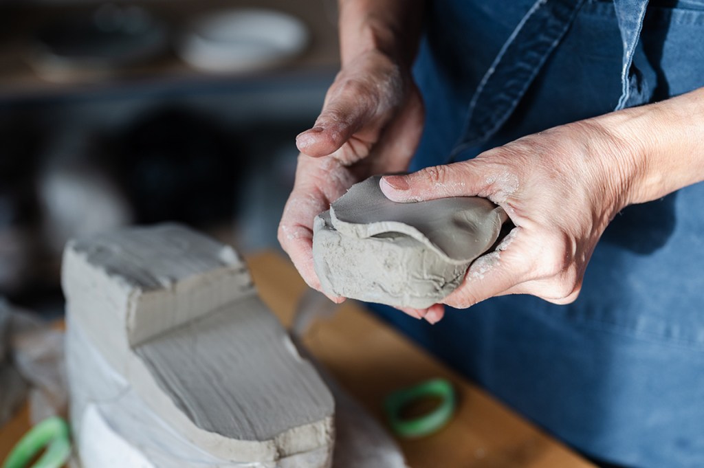 Mains d'une céramiste travaillant un morceau d'argile dans son atelier.