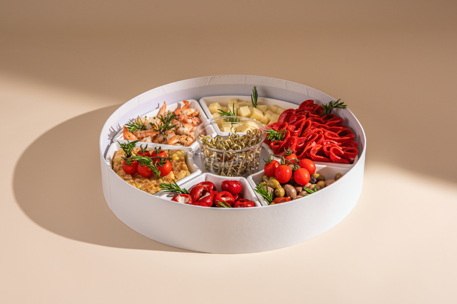 Shooting photo culinaire pour coffret apéritif : crevettes grillées, charcuterie fine et légumes frais, éclairage studio professionnel.